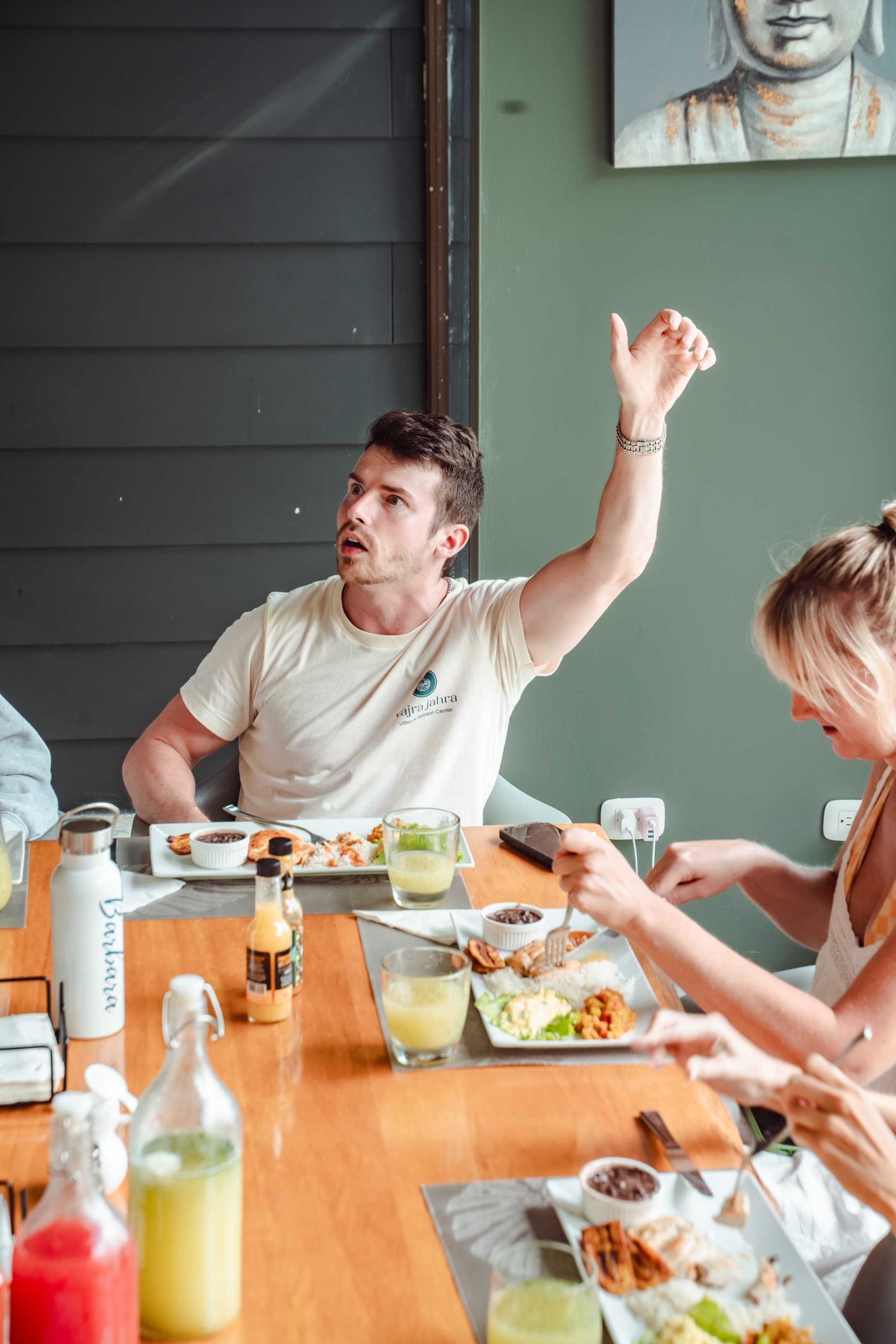 A guest speaking up while eating with other guests in Vajra Jahra's al fresco dining space.