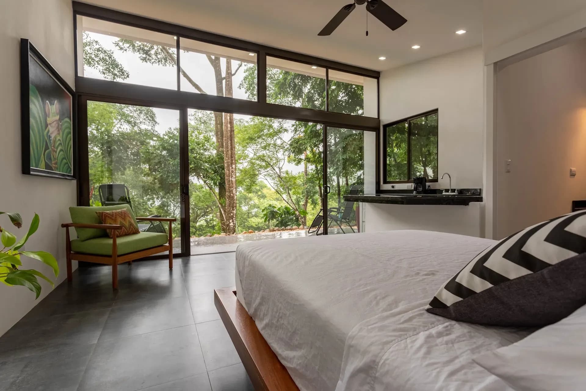 Villa bedroom with jungle views, queen bed, sitting area, and floor-to-ceiling windows at Vajra Jahra Retreat Center.