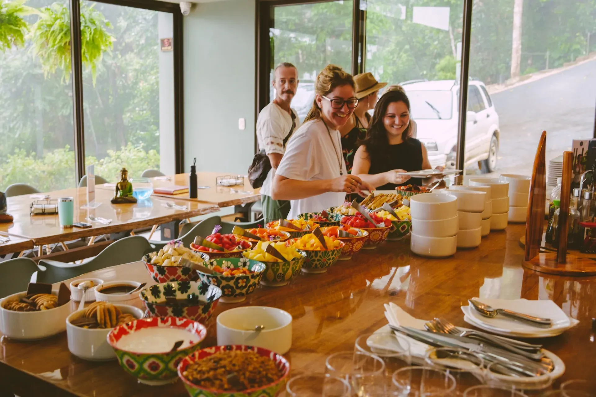 A group of people on a retreat at Vajra Jahra, smiling and looking at a colorful array of fresh local food.