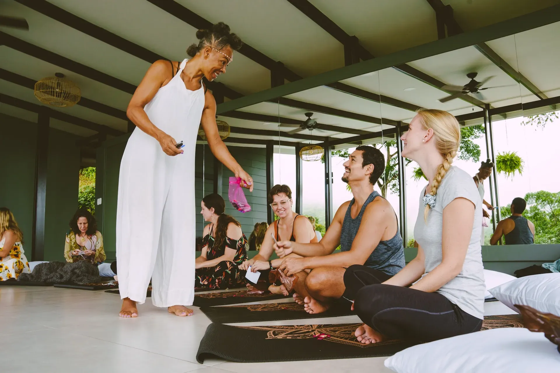 A group leader handing out items to other retreat guests in Vajra Jahra's yoga shala in Costa Rica.