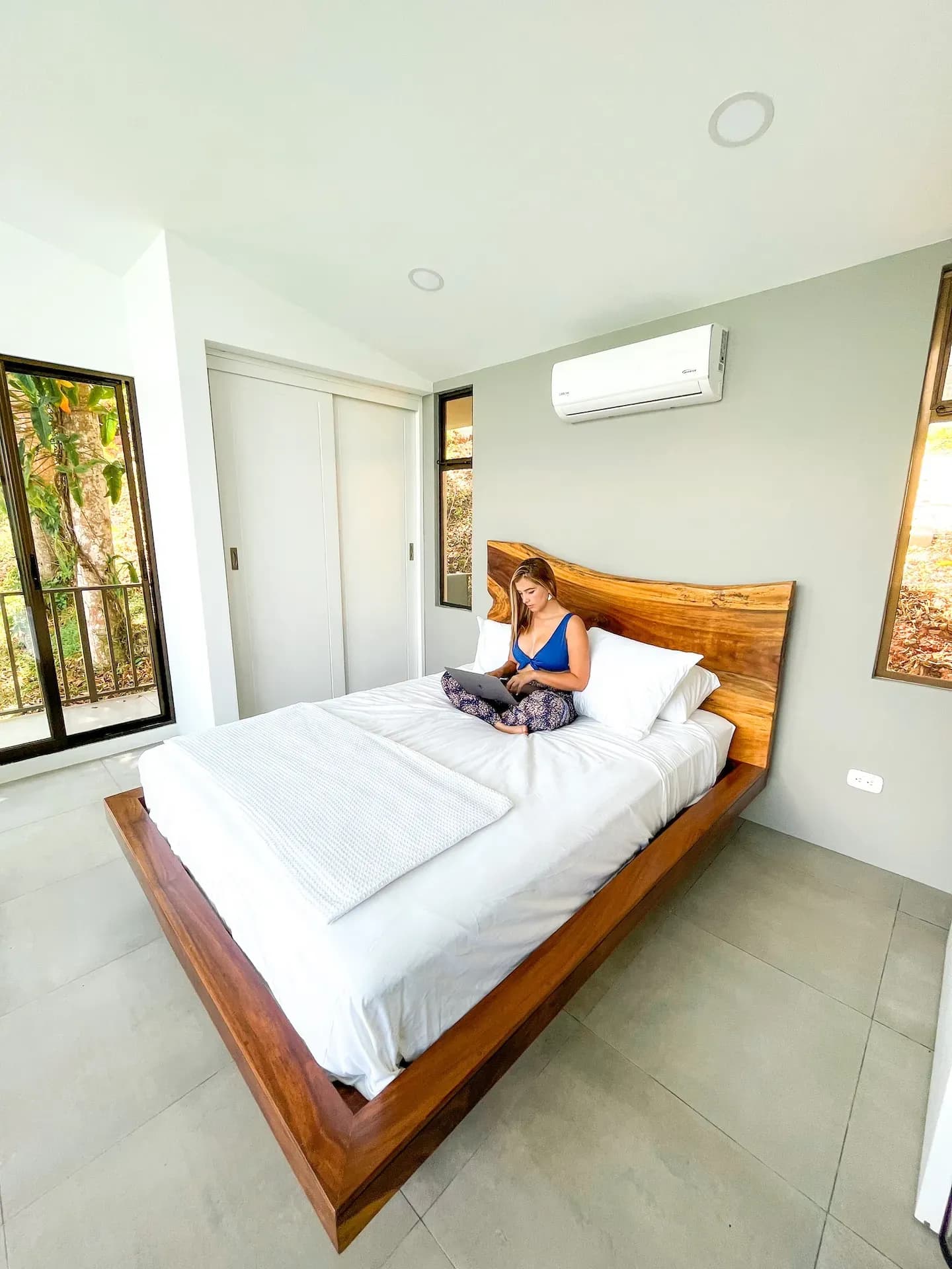 Guest relaxing on a queen bed inside a private villa at Vajra Jahra, a peaceful retreat center in Costa Rica.