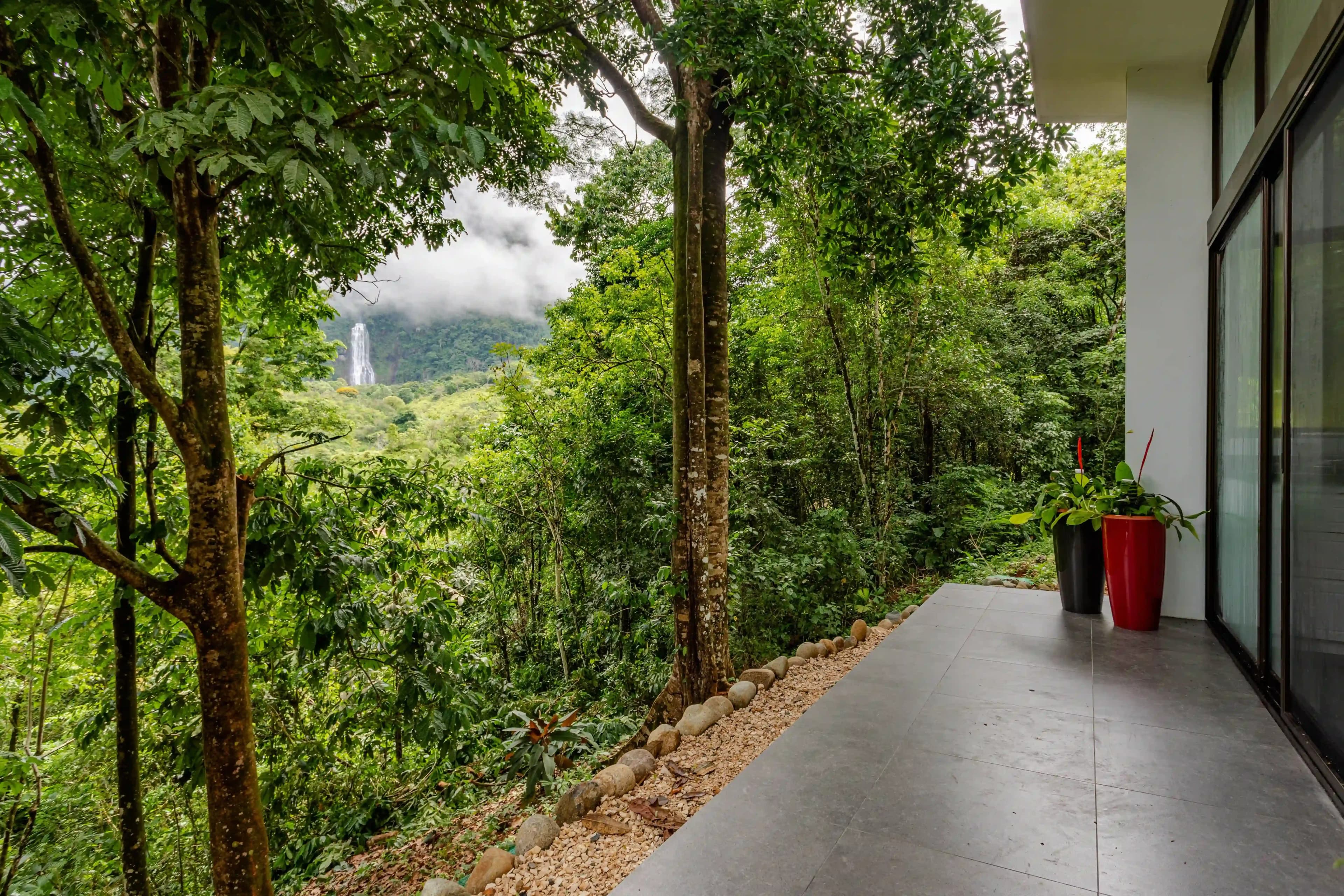 View of lush greenery and the Diamante Waterfalls from a private villa deck at Vajra Jahra wellness retreat center.