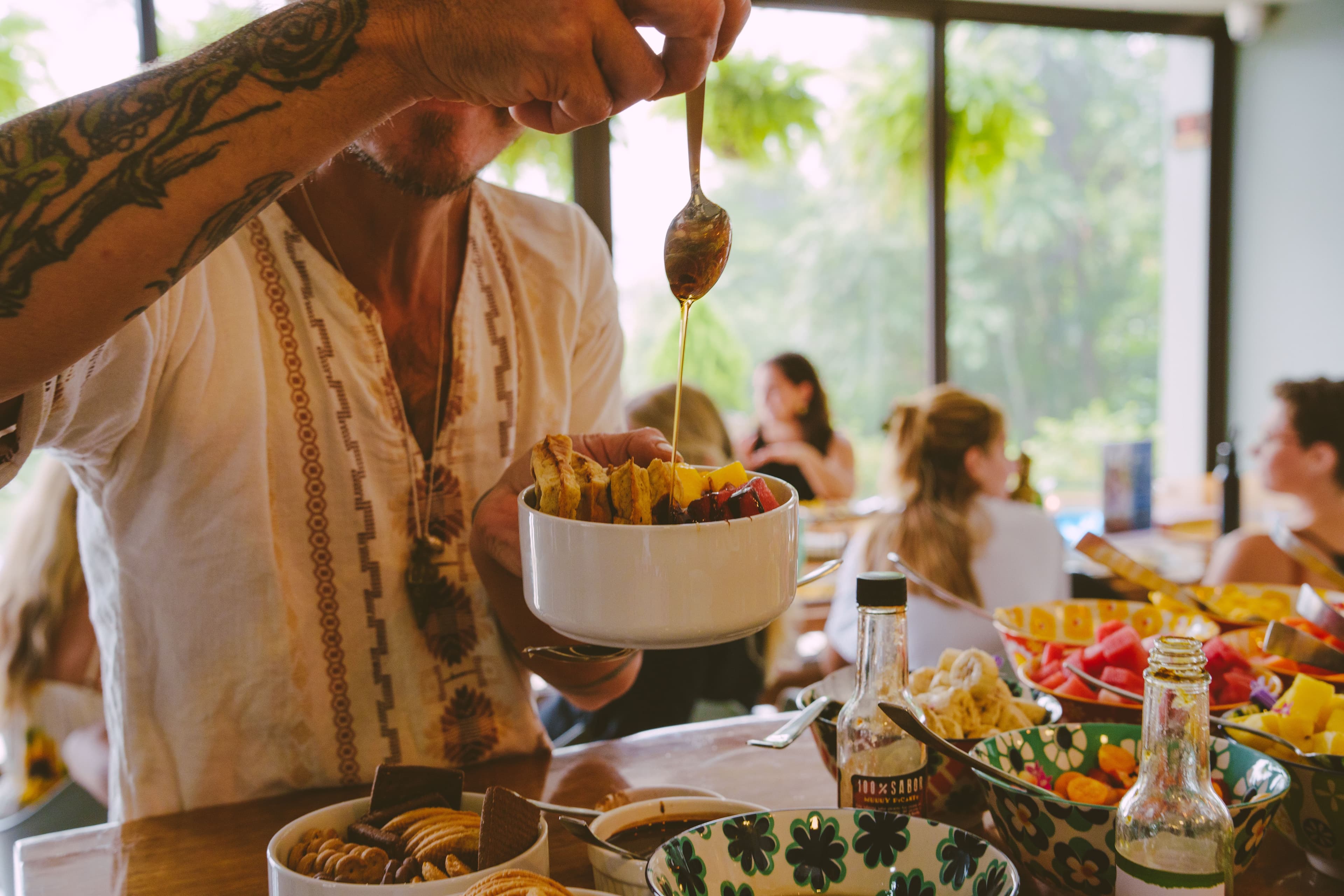 A retreat guest drizzling honey over a fruit bowl.