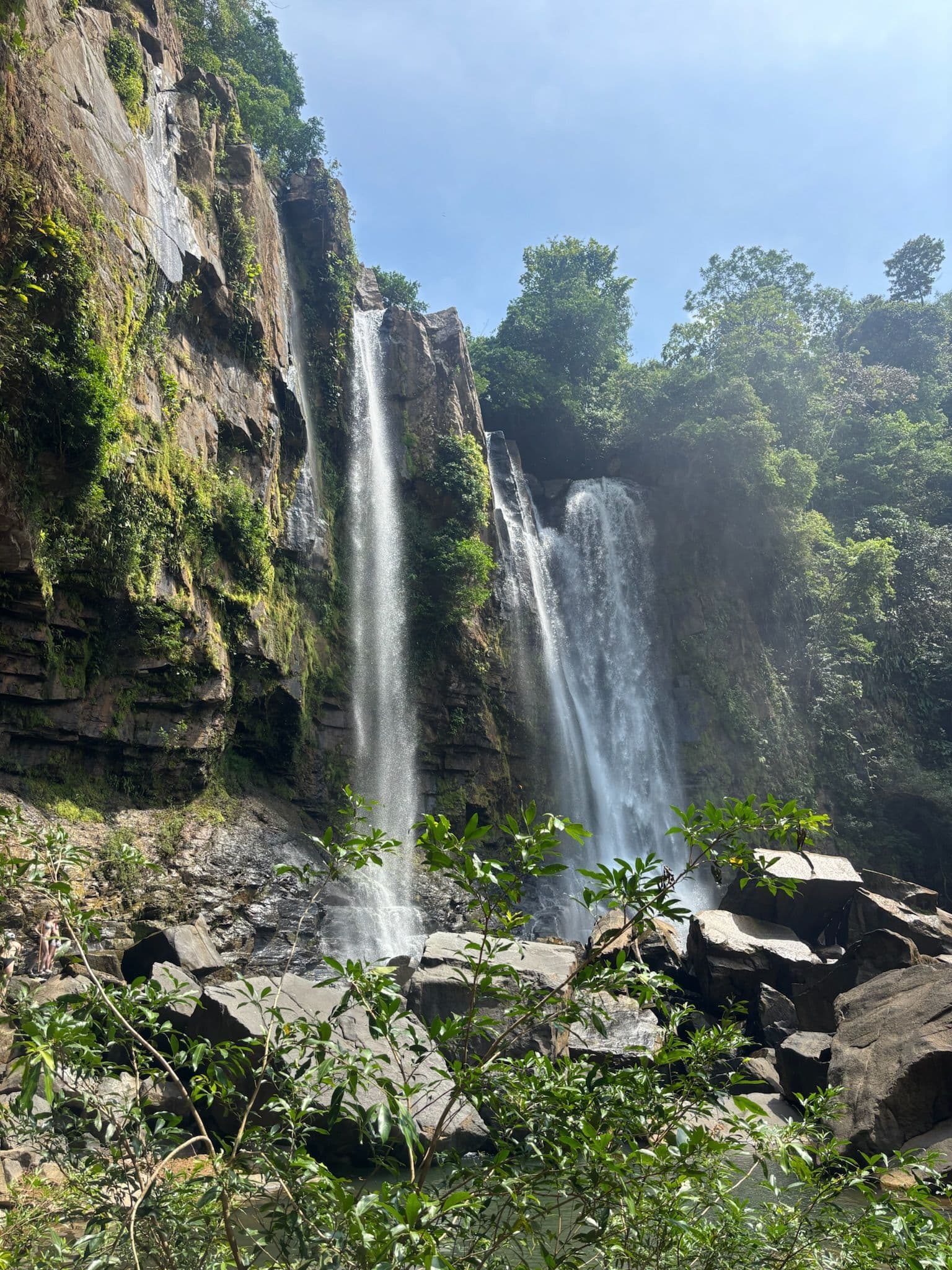 View of the Nauyaca Waterfall surrounded by lush jungle and rock formations.
