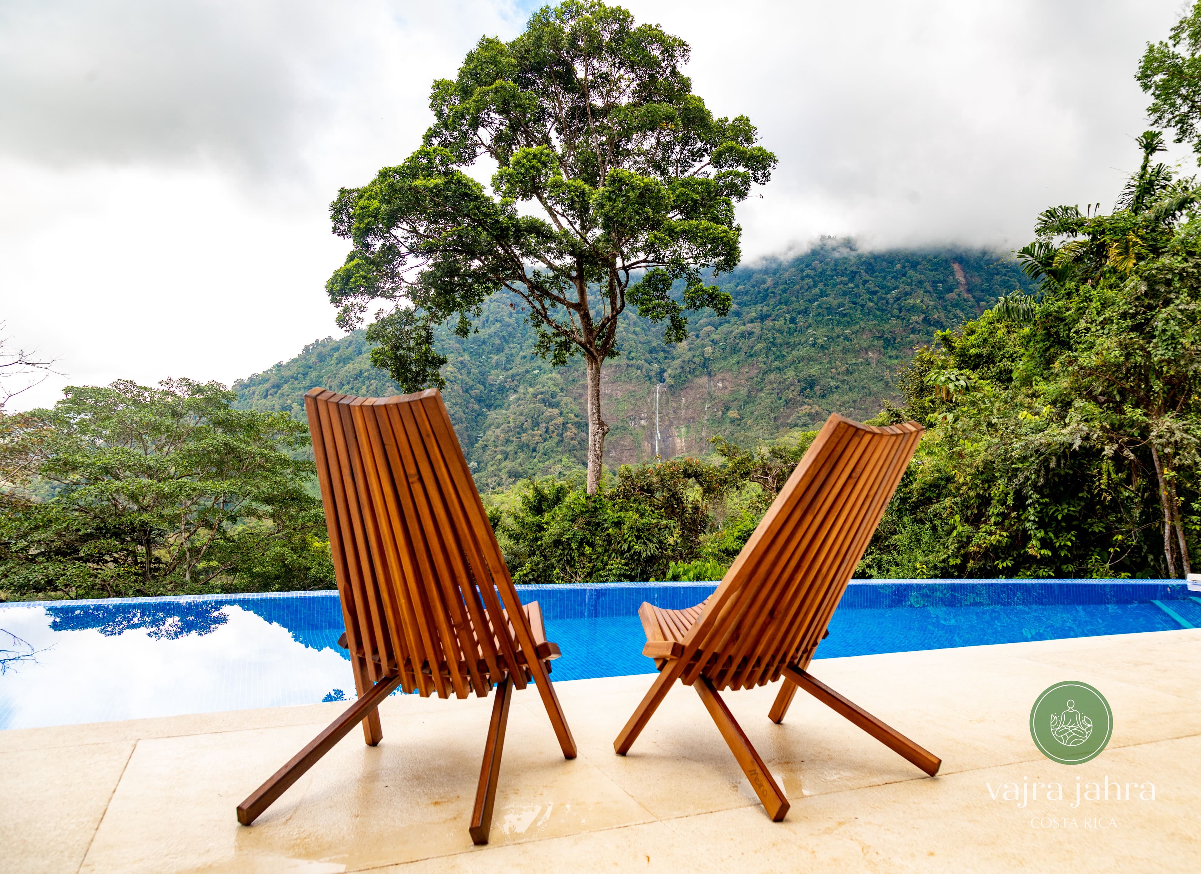 Infinity pool with wooden lounge chairs overlooking lush jungle and the Diamante Waterfall.