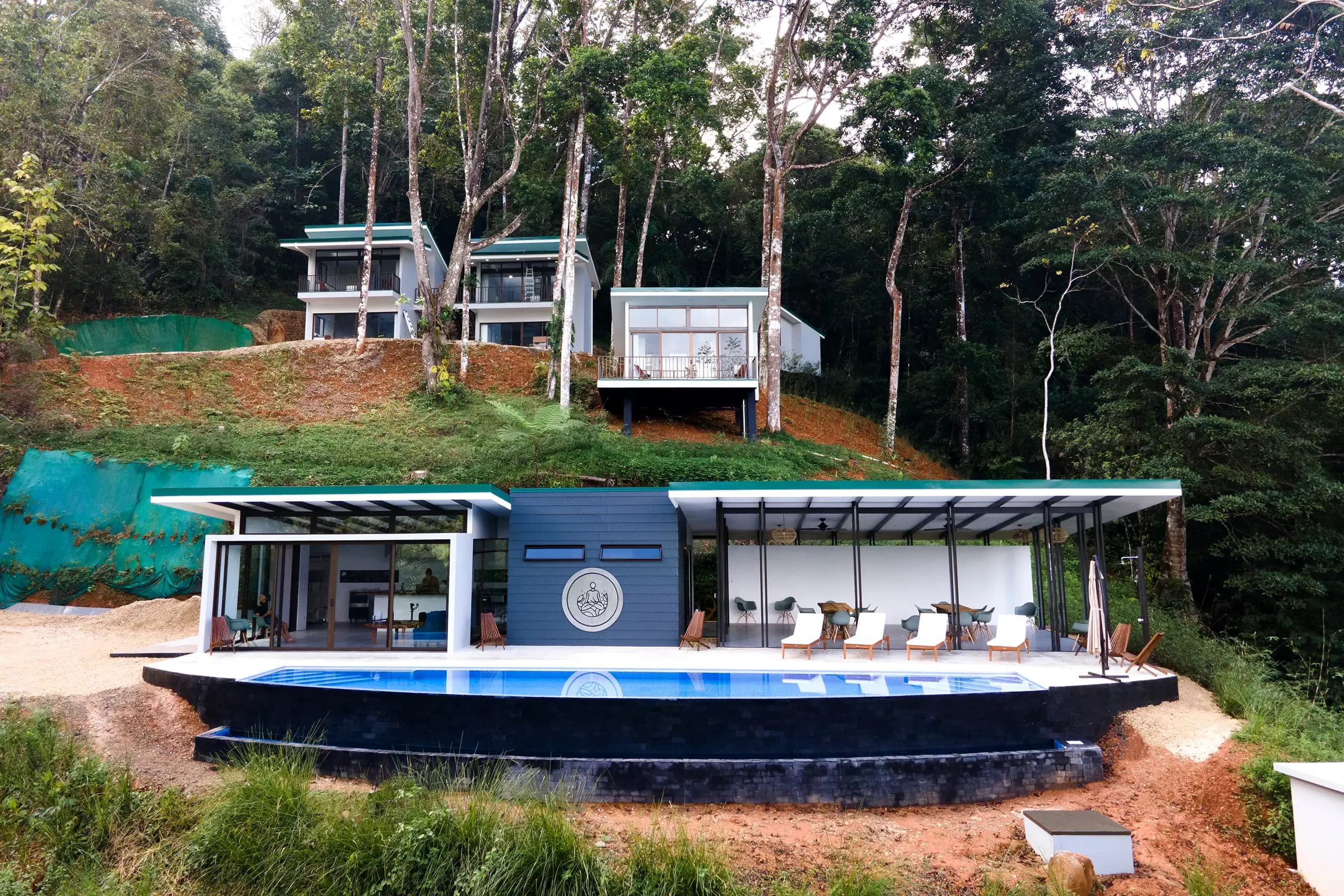 View of the Vajra Jahra wellness retreat center showing the main building, infinity pool, and three upper villas.