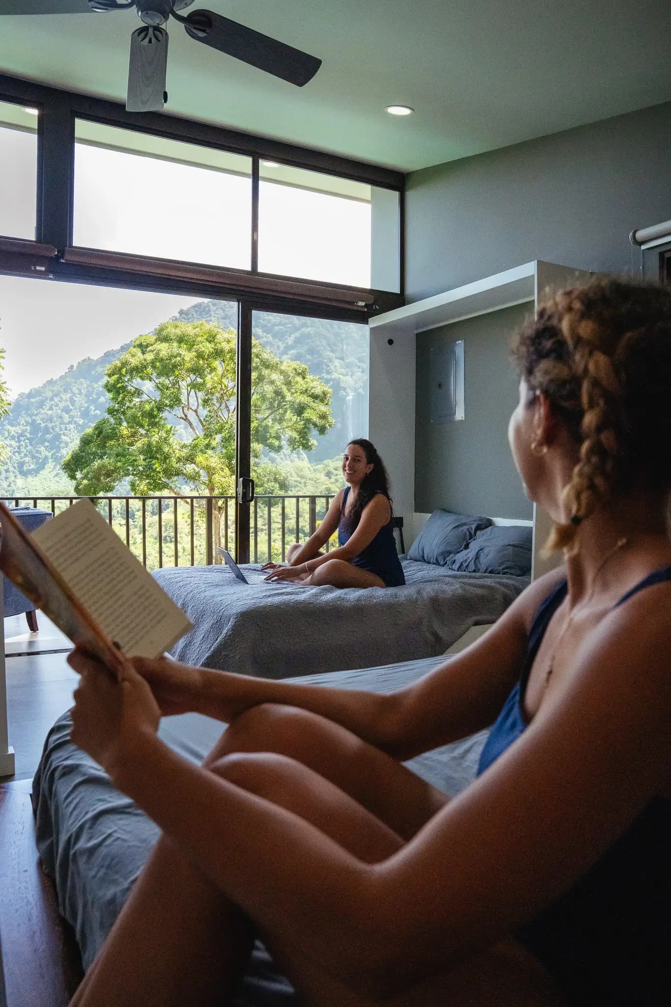 Guests reading and enjoying the minimalist villa with large windows and nature views at Vajra Jahra Retreat Center, perfect for a peaceful Yoga Retreat in Costa Rica.