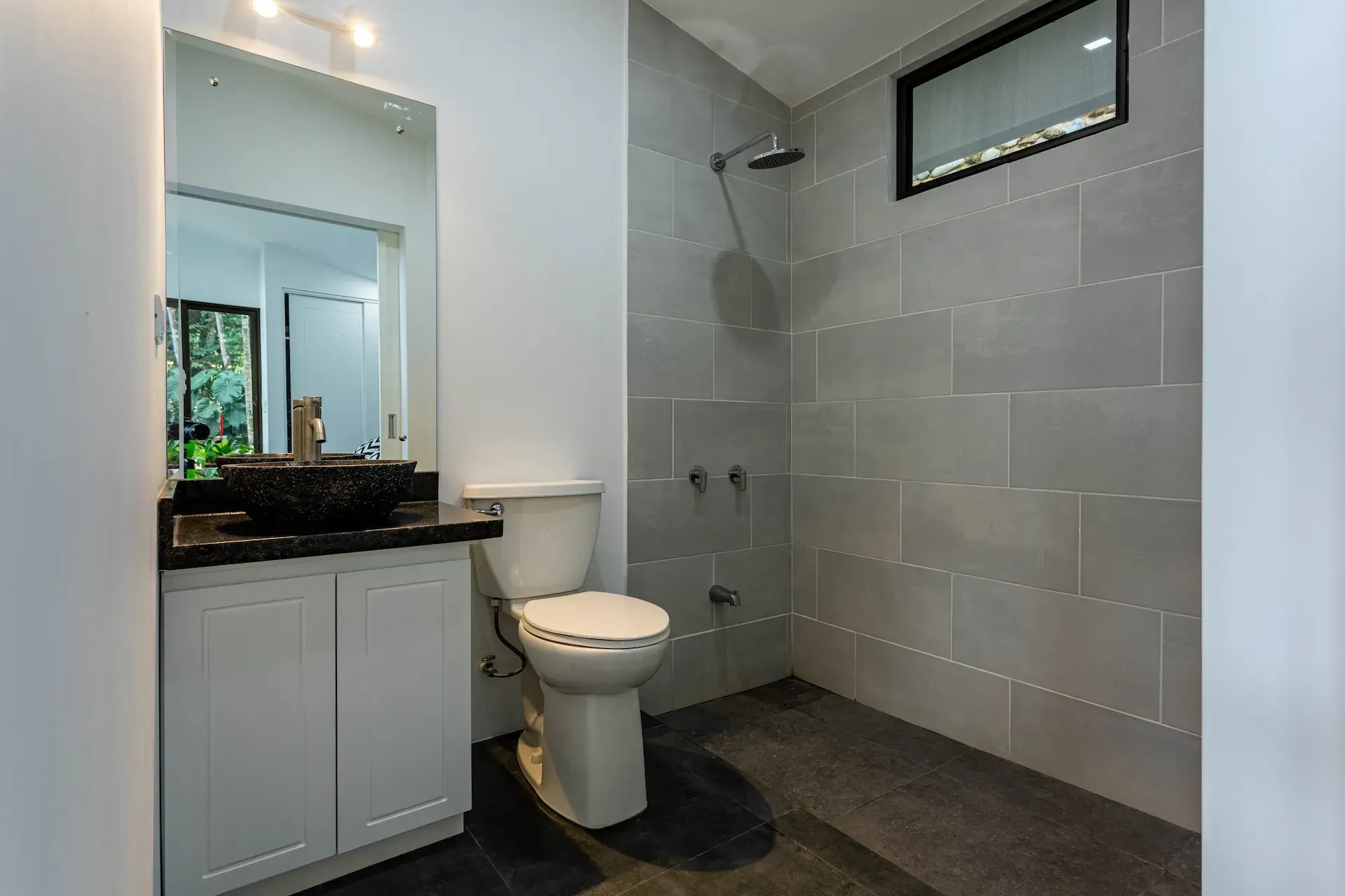Modern private bathroom at Vajra Jahra, a Costa Rica Retreat Center, featuring a spacious walk-in shower and minimalist design.
