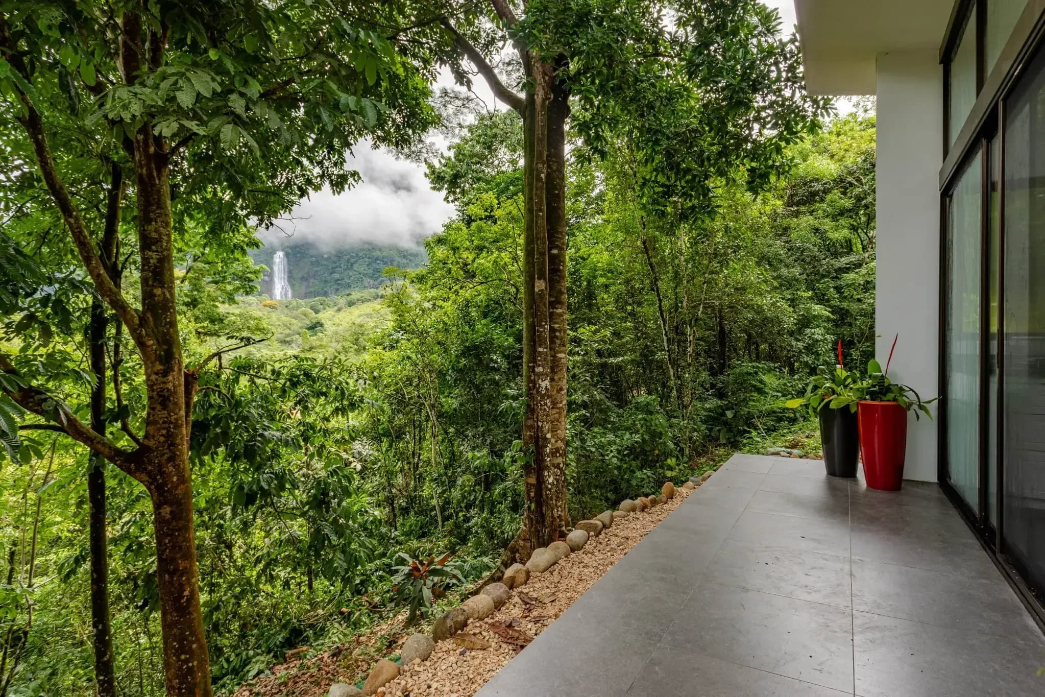 Villa terrace at Vajra Jahra, a Costa Rica Retreat Center, overlooking lush jungle with a distant view of the Diamante Waterfall.