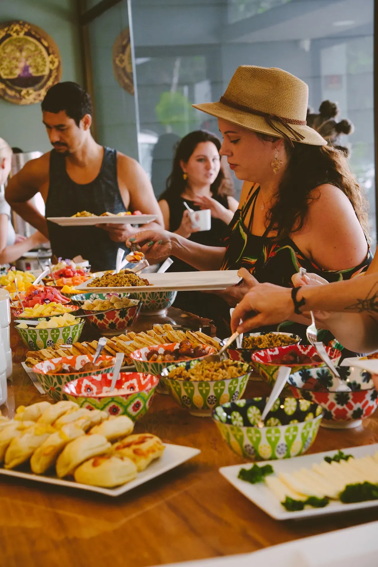 A woman serving herself from a buffet-style spread of colorful food at Vajra Jahra Costa Rica retreat center.