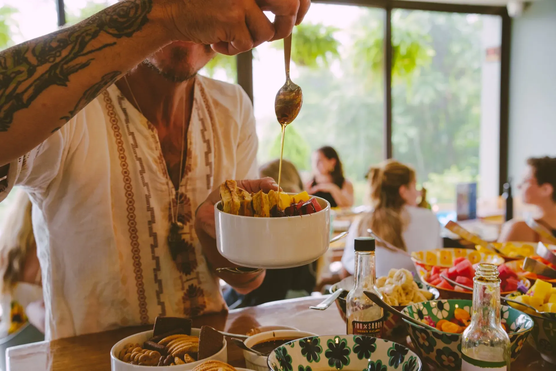 Guest drizzling honey over a tropical fruit bowl at Vajra Jahra, a Costa Rica Retreat Center known for its nourishing, nature-inspired meals.