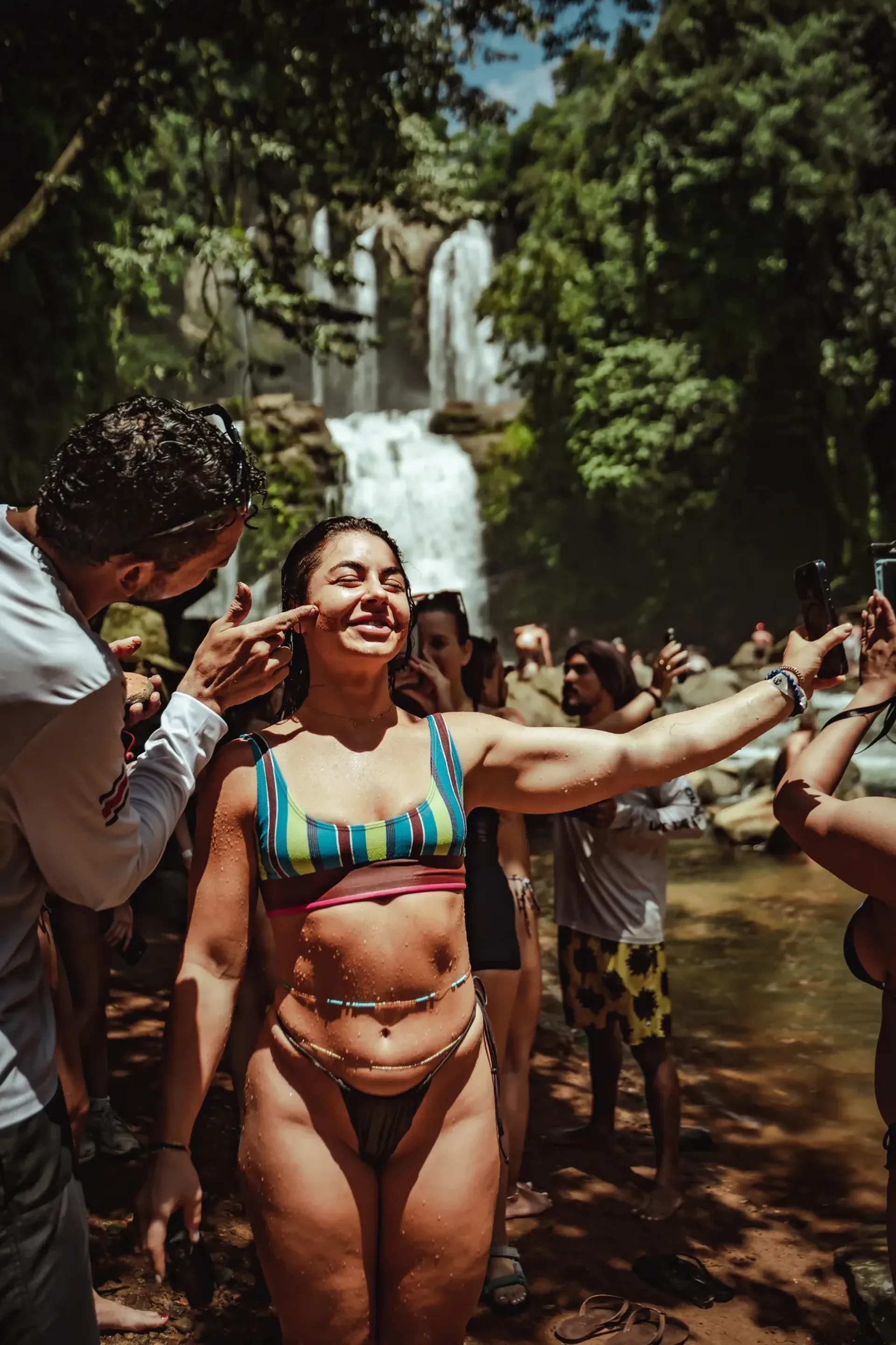 A joyful group celebrating by a jungle waterfall during an excursion at Vajra Jahra, a Costa Rica Retreat Center.