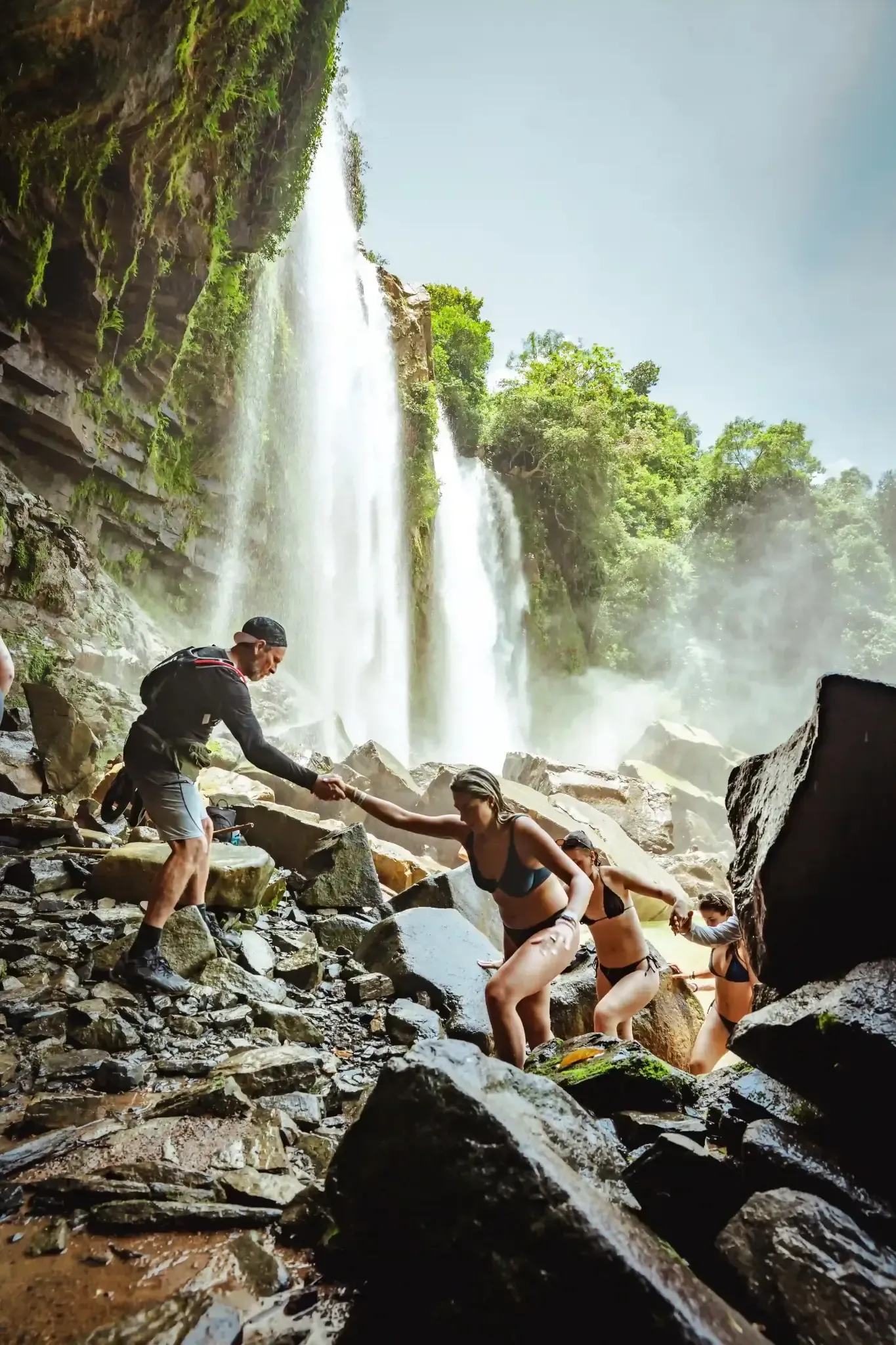 Guests from the Costa Rica Retreat Center Vajra Jahra exploring the rugged terrain beside a mist-filled tropical waterfall.