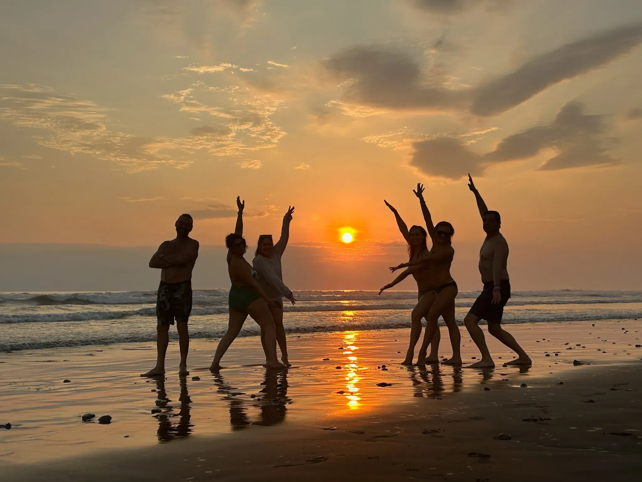 Friends celebrating during a sunset beach outing hosted by Vajra Jahra, an immersive Costa Rica Retreat Center.