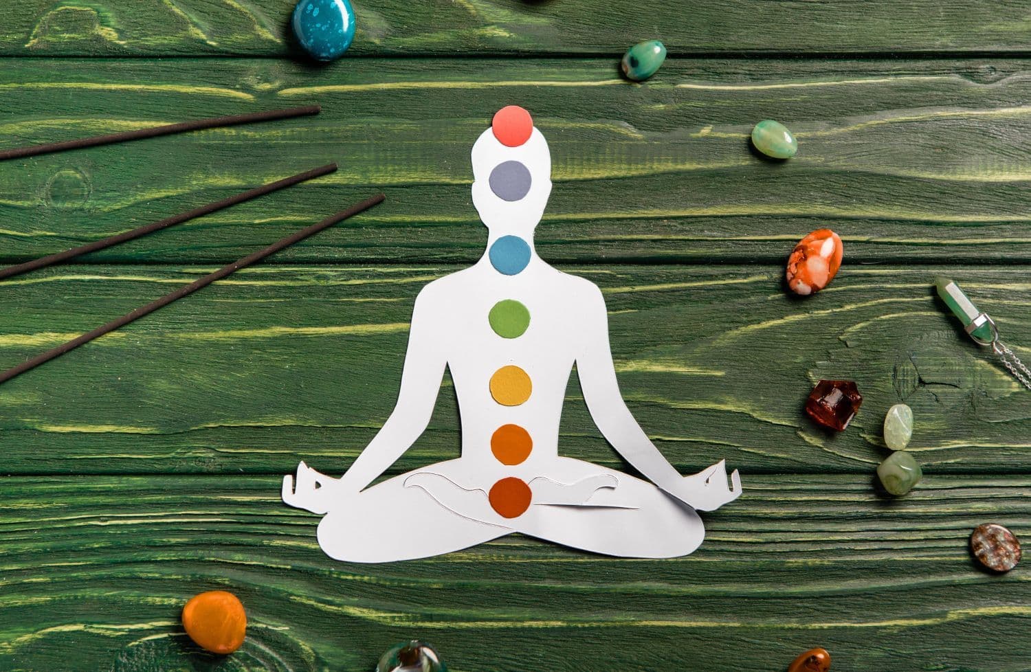 A paper cutout of a meditating yogi with colored circles to indicate the location of the seven chakras.