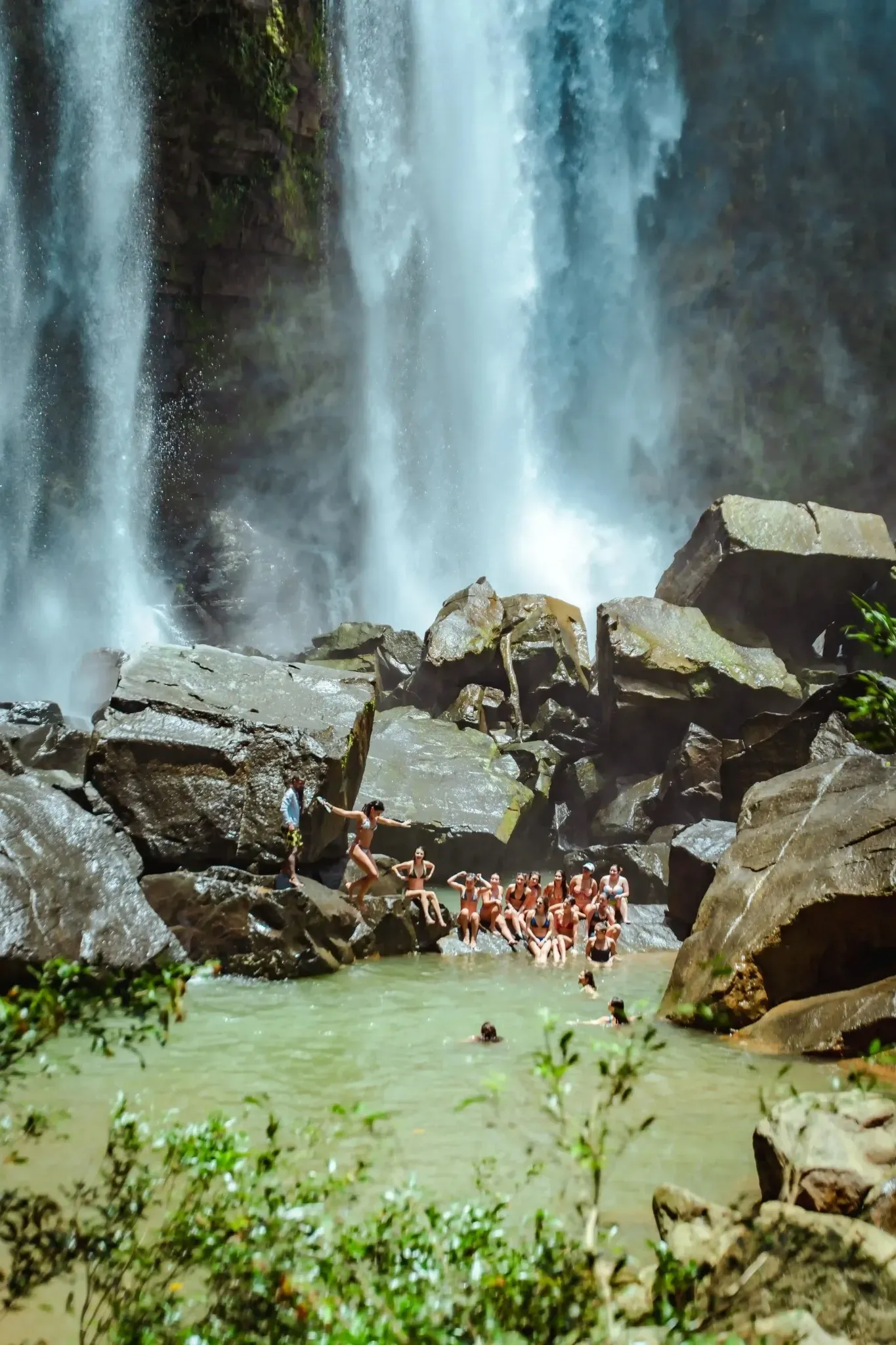 Guests swimming beneath majestic waterfall near all inclusive villas in Costa Rica.