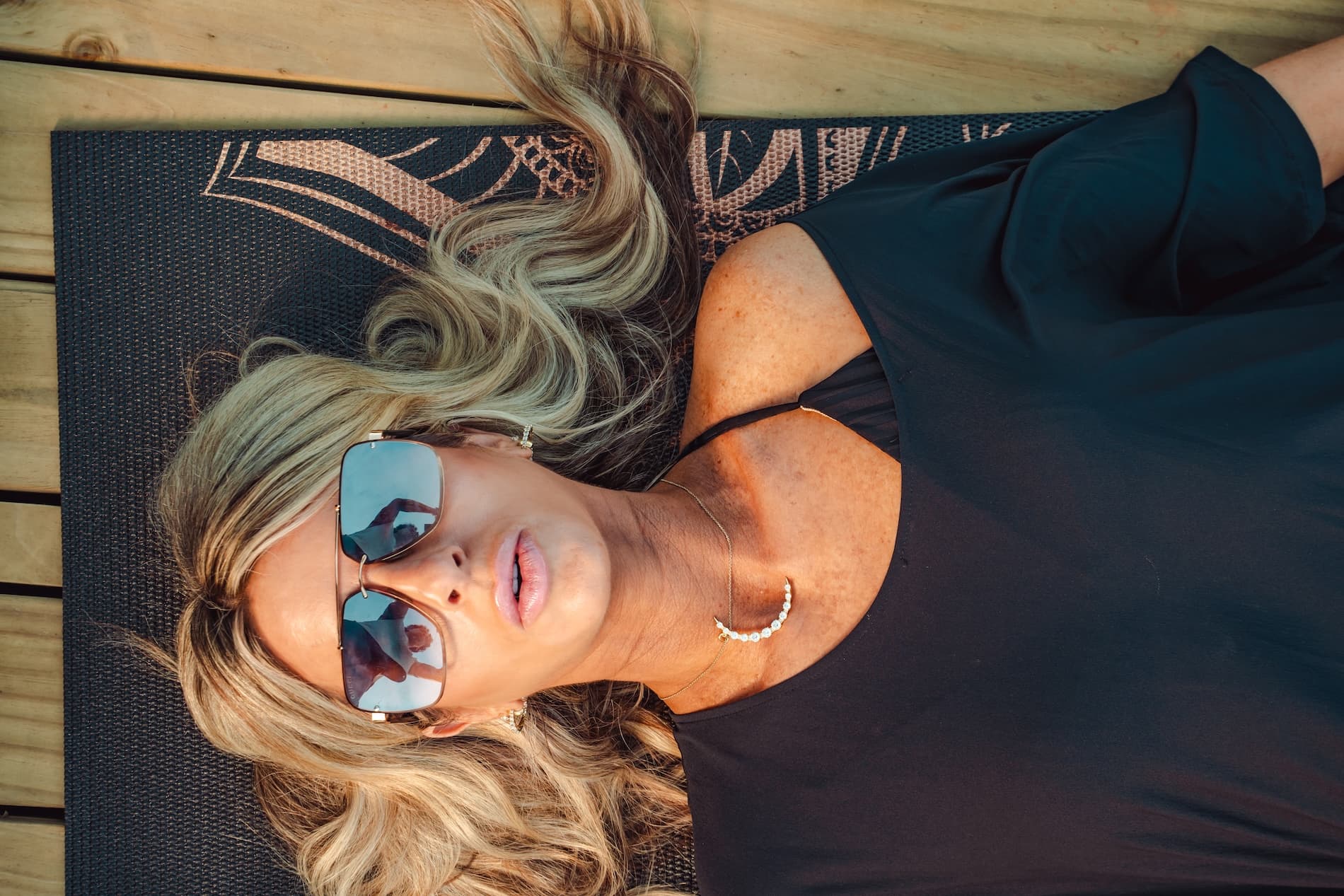 A woman with sunglasses peacefully lying face up on a yoga mat at Vajra Jahra Retreat Center.