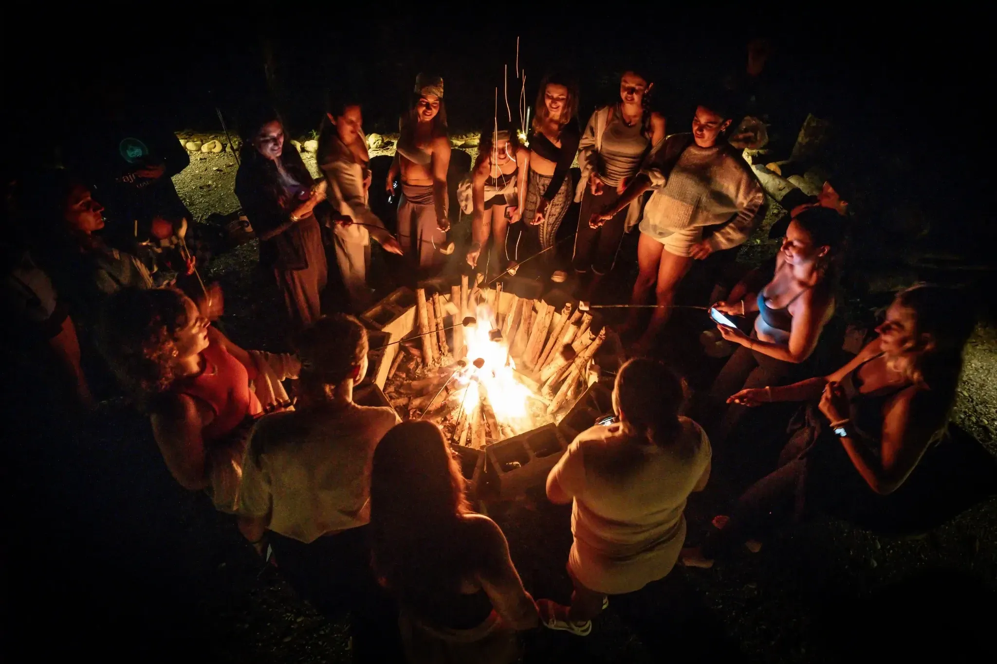 Guests at Vajra Jahra Retreat Center gathered around a bonfire at night, sharing a group ceremony under the stars.