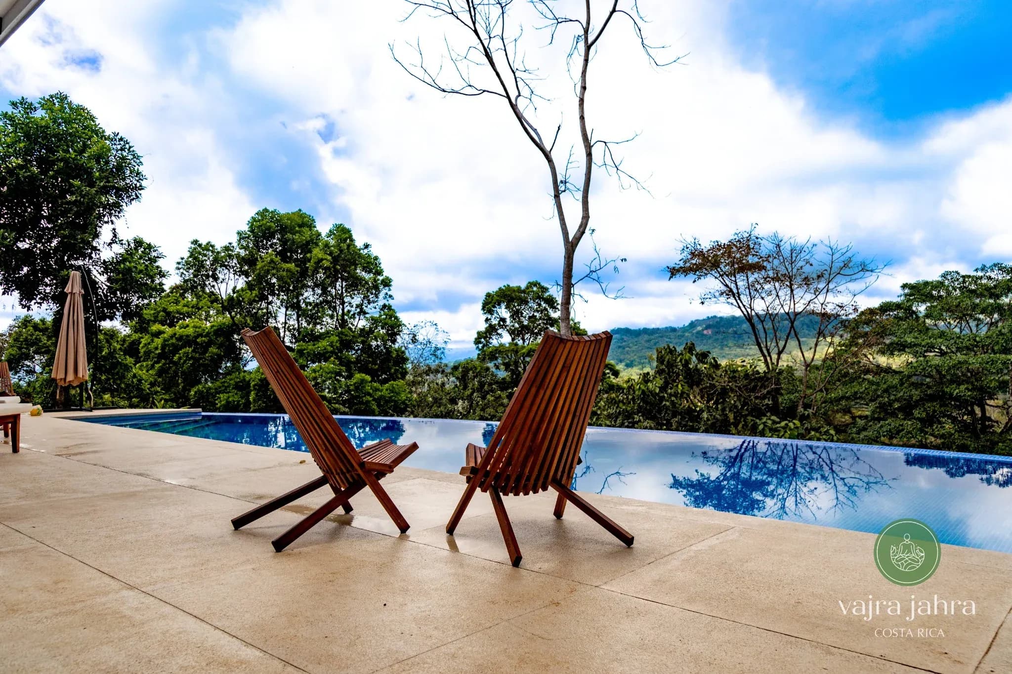 Infinity pool with wooden lounge chairs overlooking the jungle at Vajra Jahra Retreat Center, a serene setting for family reunion vacation rentals.
