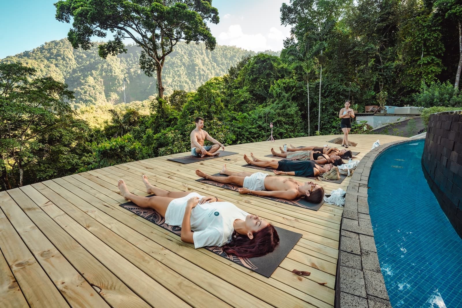 Retreat guests relaxing on yoga mats outdoors with rainforest view at Vajra Jahra Retreat Center in Costa Rica