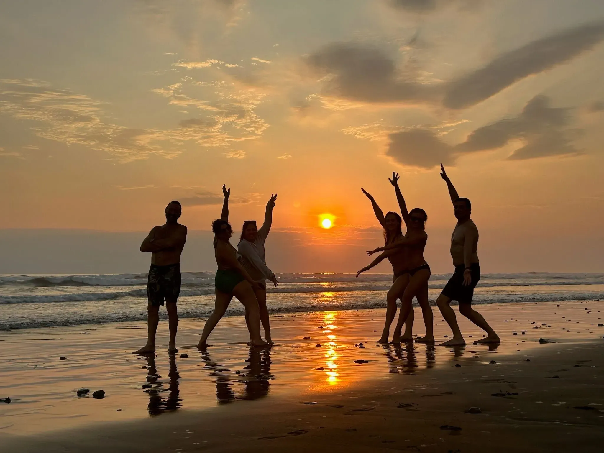 Group of retreat participants posing at sunset by the ocean as part of their Yoga Retreat in Costa Rica at Vajra Jahra Retreat Center.