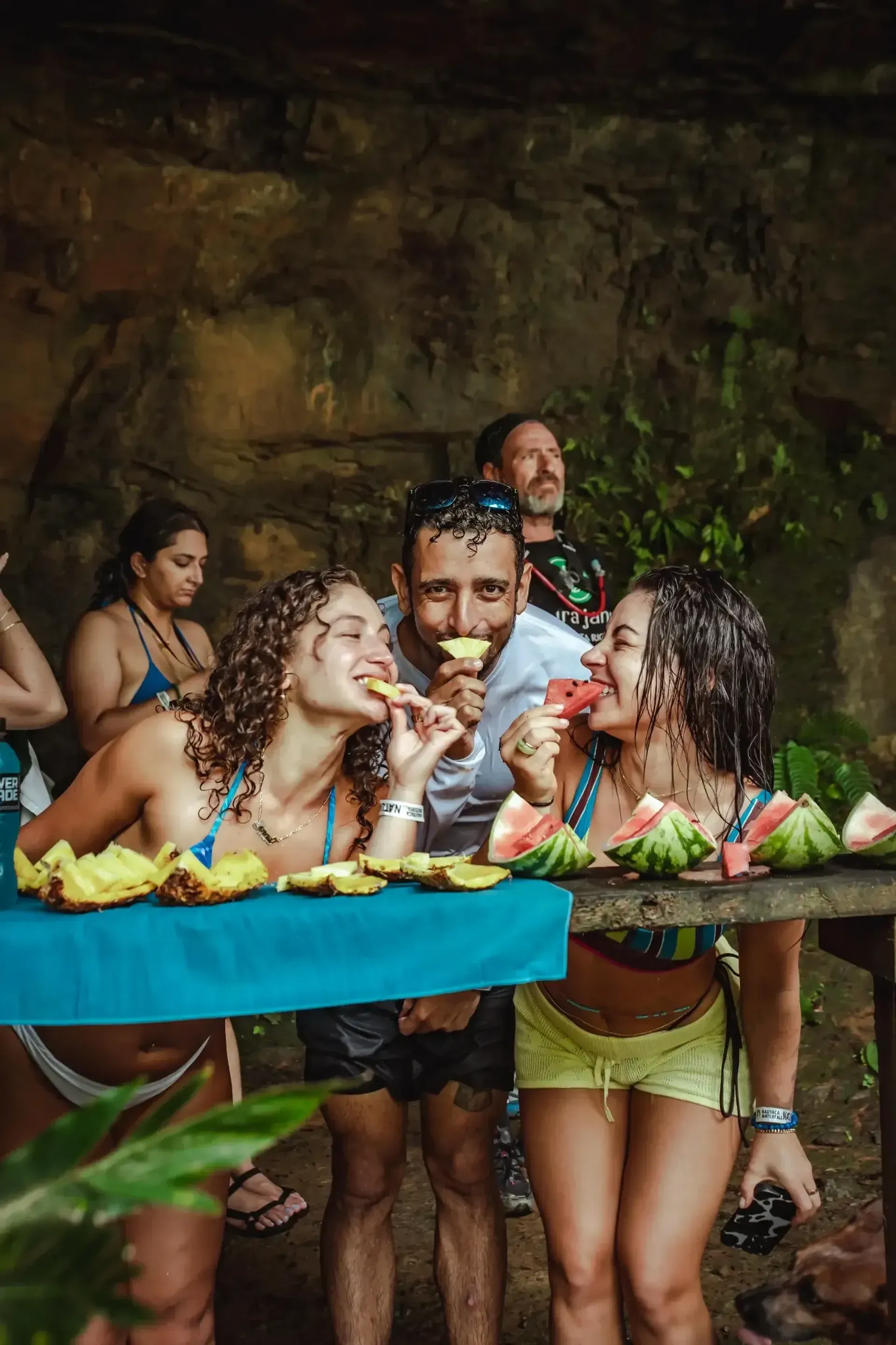 Guests sharing tropical fruit near natural pools at Vajra Jahra Retreat Center, a relaxing setting for family reunion vacation rentals.