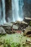Guests from Vajra Jahra Retreat Center swimming at the base of a majestic waterfall surrounded by lush jungle and rock formations.