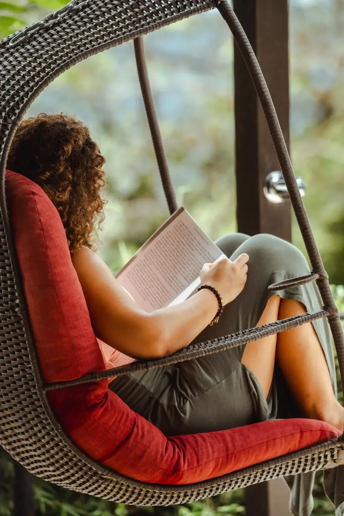 Woman relaxing in a hanging chair while reading at Vajra Jahra Retreat Center, enjoying the peaceful atmosphere of a Costa Rica retreat center.
