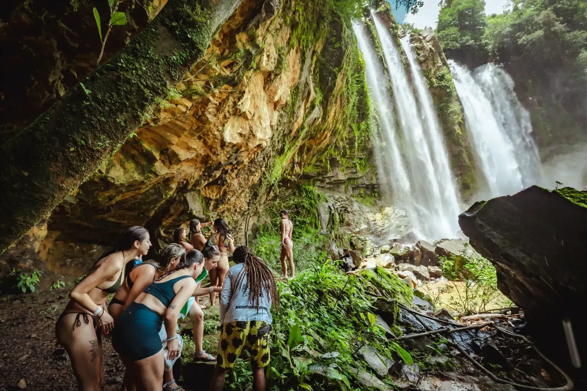 A group explores the lush jungle beside a powerful cascade at Diamante Waterfall Costa Rica, embodying the adventurous spirit guests experience at Vajra Jahra.