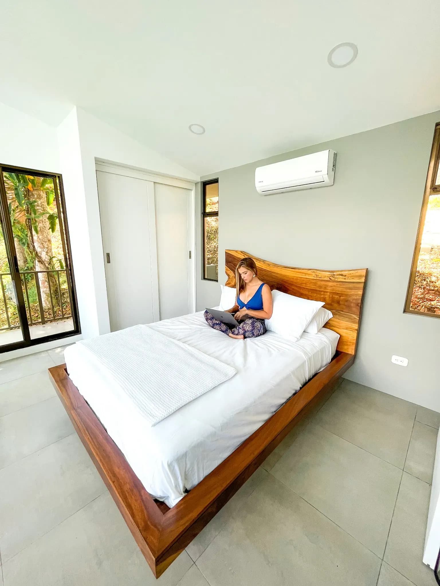 Corporate retreat guest working on laptop sitting on the queen bed in one of our villas at Vajra Jahra.